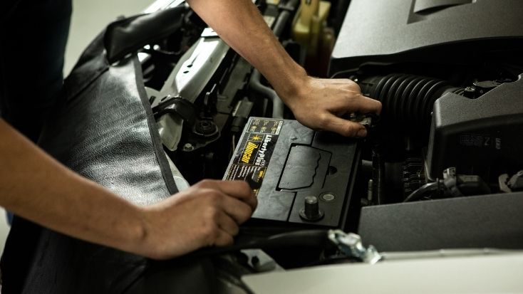 Imagen de mecánico haciendo mantenimiento a una batería de carro